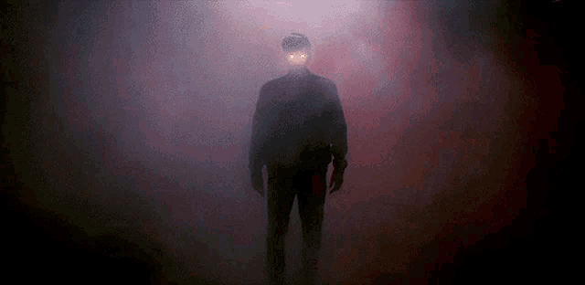 a man with glowing eyes is standing in a dark room