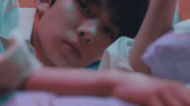 a close up of a man laying on a bed with his head on his hand .