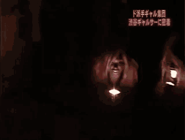 a woman is sitting in the dark with a candle in front of her .