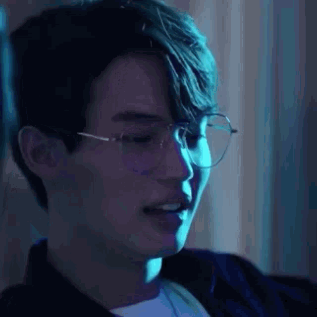 a close up of a person wearing glasses in a blue light .