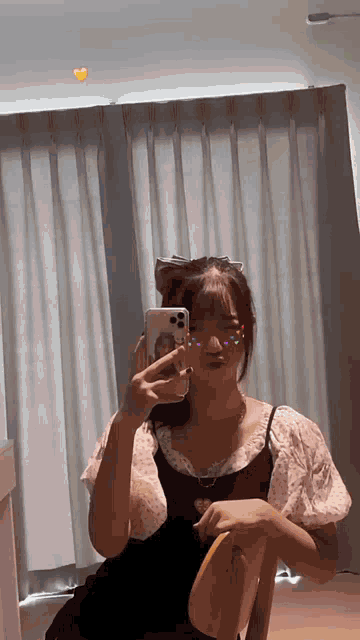 a woman is taking a picture of herself in a mirror while sitting in a chair .