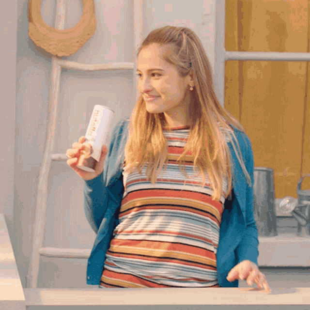 a woman in a striped shirt is holding a can that says ' nutella '