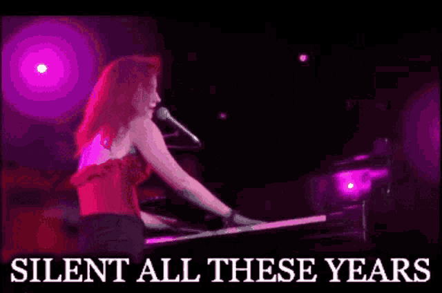 a woman is singing into a microphone while playing a piano and the words silent all these years are above her