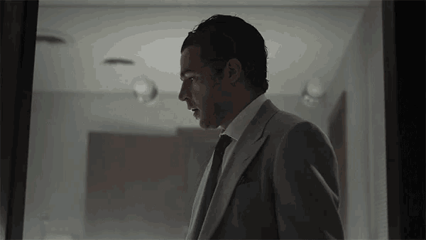 a man in a suit stands in a dark room