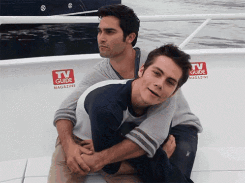 two men sitting on a boat with tv guide magazine stickers on the side