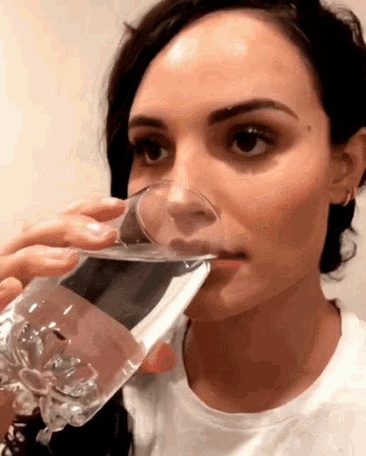 a woman is drinking a glass of water from a broken glass .