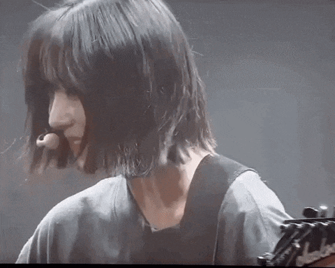 a woman with short hair is playing a guitar .