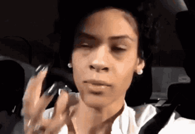 a woman with long nails is sitting in a car