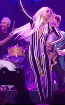 a woman in a striped jumpsuit stands on a stage