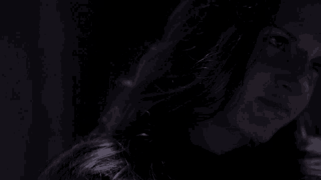a close up of a woman 's face in the dark with a serious look on her face .