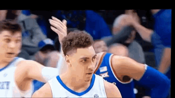 a basketball player in a blue and white uniform is being fouled by another player .