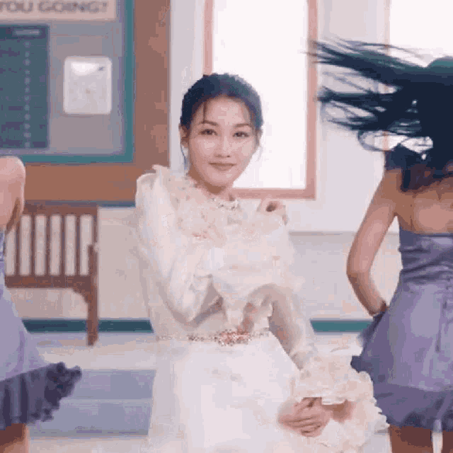 a woman in a white dress is dancing in front of a sign that says you going ?