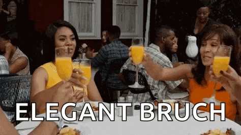 a group of people are sitting at a table toasting with orange juice glasses .