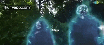 a group of people are standing next to each other in a forest surrounded by trees and glowing in the dark .