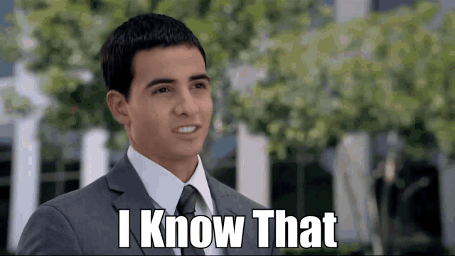 a man in a suit and tie is smiling and says " i know that "