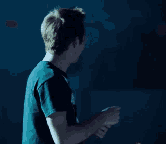 a man in a black shirt is standing in a dark room holding something in his hand .