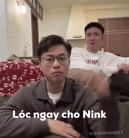 two young men are sitting on a couch and one of them is wearing a shirt that says tommy