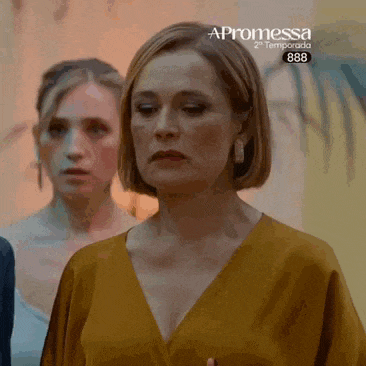 a woman in a yellow top is standing in front of a painting with the word promessa on it