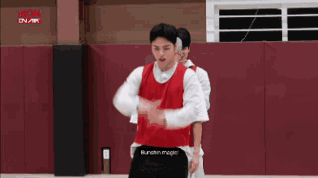 a man in a red vest is standing next to a man in a white shirt on a basketball court .