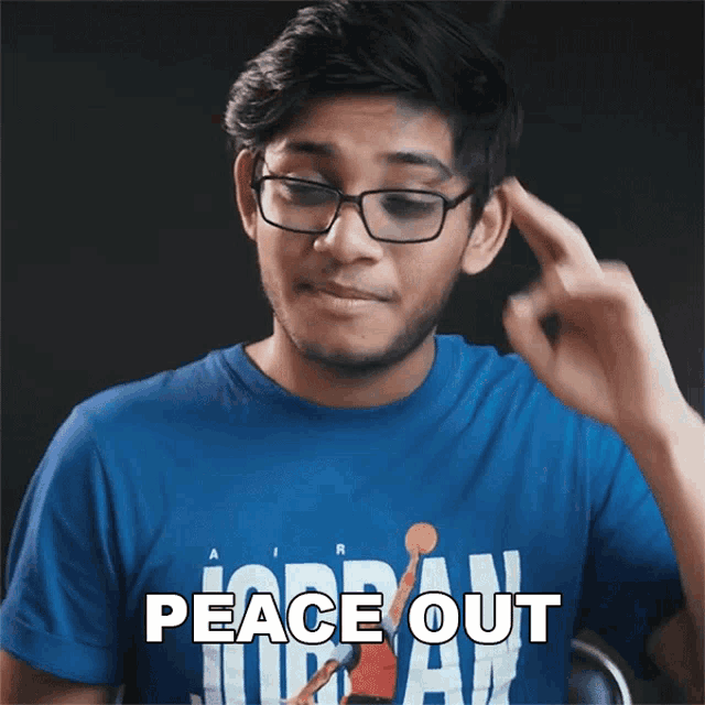 a man wearing glasses and a blue shirt that says peace out on it