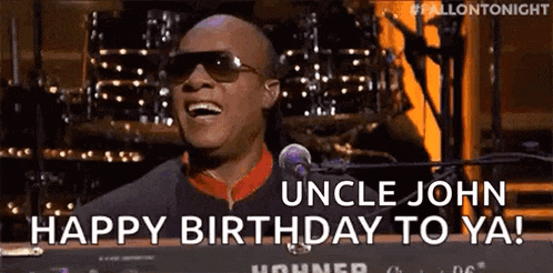 a man wearing sunglasses is singing into a microphone and saying `` uncle john happy birthday to ya '' .
