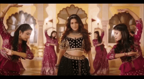 a group of women are dancing in a room in traditional indian costumes .