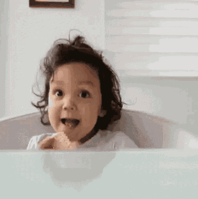 a little girl is sitting in a bathtub eating a cracker