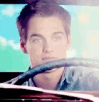 a young man driving a car with a steering wheel in his hand
