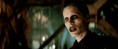 a close up of a person dressed as the joker looking at another person .