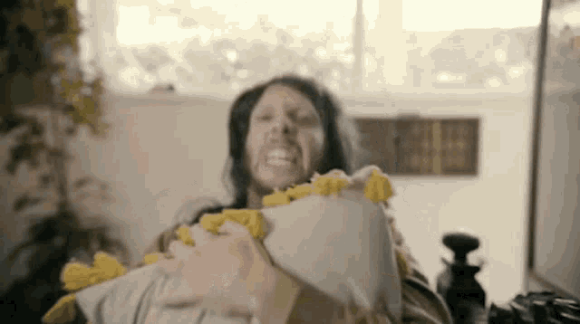 a man with a beard is holding a pillow in his hands and screaming .
