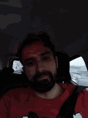 a man with a beard wearing a red shirt that has the letter n on it