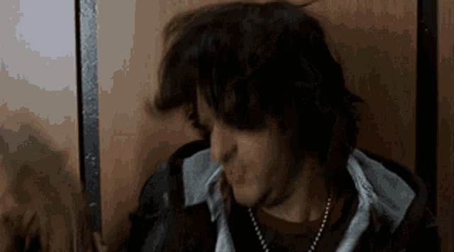 a man with long hair is blowing his hair in the wind