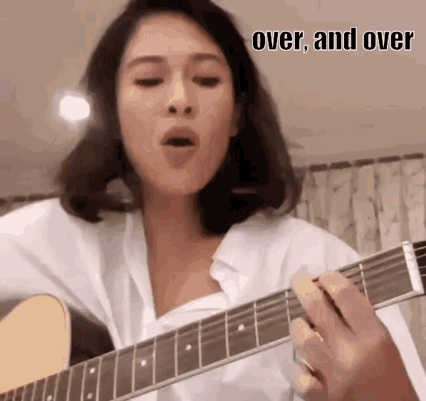 a woman is singing while playing a guitar with the words over and over written on the bottom .