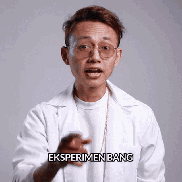 a man wearing glasses and a lab coat has the word eksperimentenbang on his chest