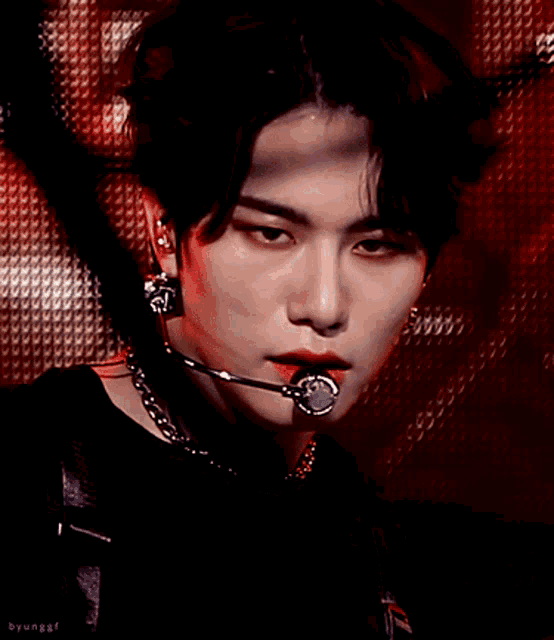 a close up of a person wearing a microphone and a necklace with the word byung on the bottom