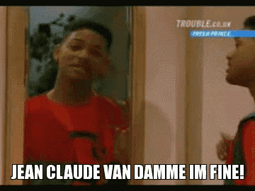 a man in a red shirt is looking at himself in a mirror and saying jean claude van damme im fine !