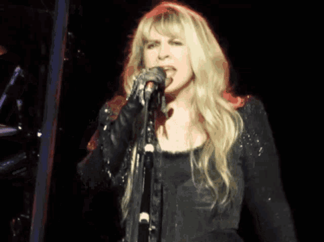 a blonde woman singing into a microphone on stage