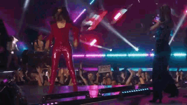a woman in a red leather suit is standing on a stage in front of a crowd .