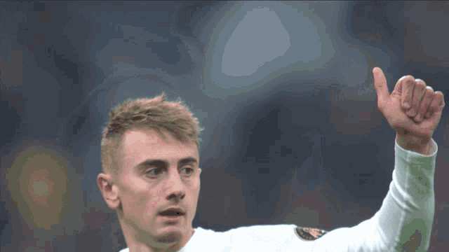 a soccer player wearing a white shirt with the letter a on it waves his hand