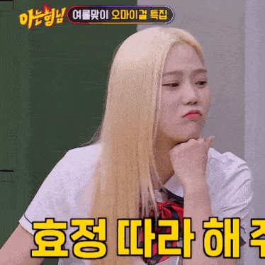 a girl with blonde hair is sitting in front of a sign that says " korean "