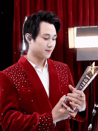 a man in a red jacket is holding a trophy that says ' a ' on it