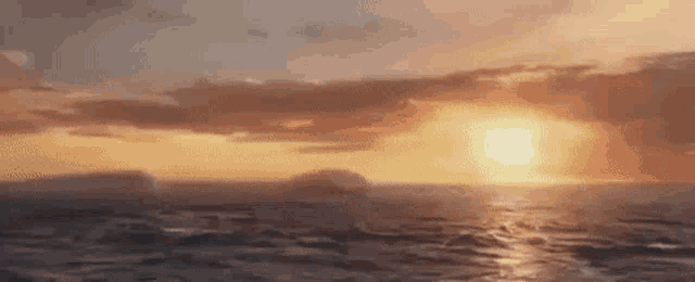 the sun is setting over the ocean with icebergs in the background .