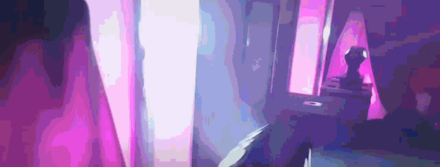 a person is playing a video game in a dark room with a purple light behind them .