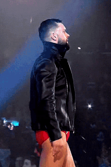 a man with a beard wearing a black leather jacket and red shorts