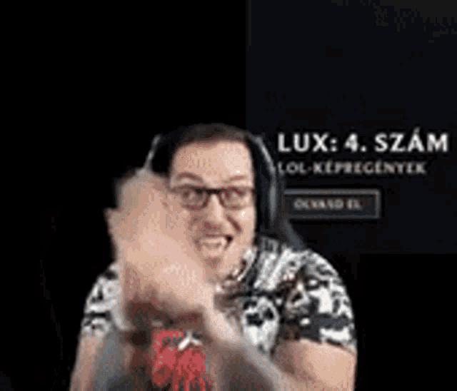 a man wearing headphones and glasses is waving his hands in front of a screen that says lux 4 .