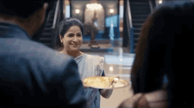 a woman is holding a plate of food in front of a man and two women .