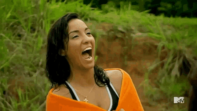 a woman wrapped in an orange towel is laughing in a field .