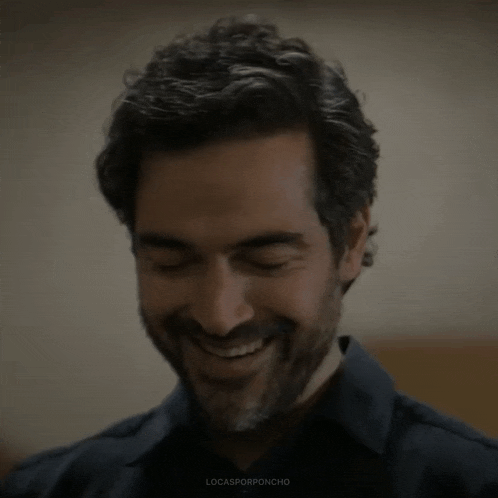 a man with a beard is smiling with his eyes closed in a close up of his face .