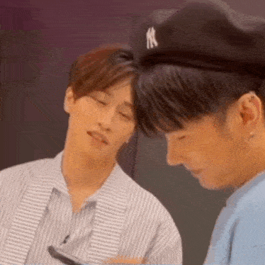two men are sitting next to each other looking at a cell phone .