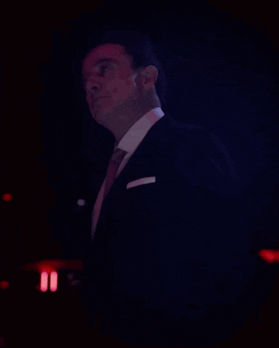 a man in a suit and tie stands in front of a blue background